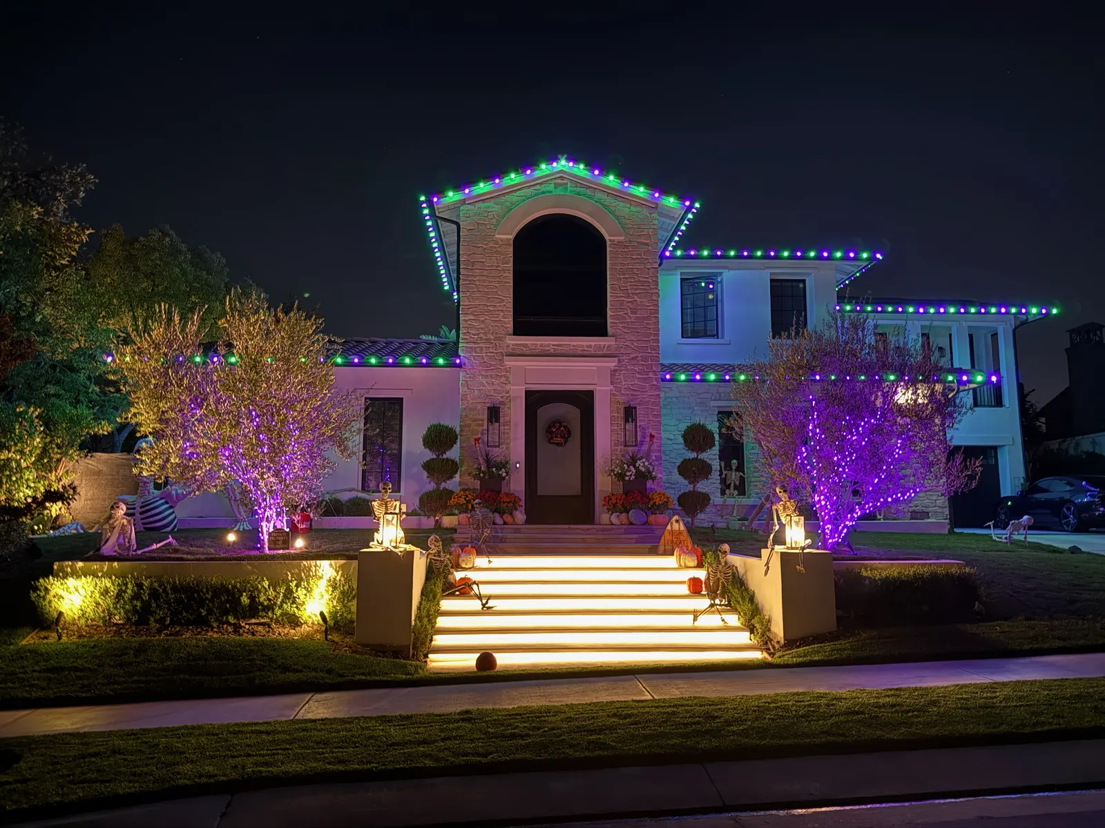 Full home Halloween lighting with skeletons and purple tree lights